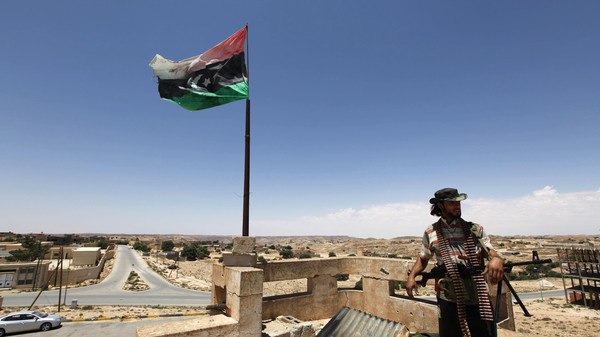 A rebel fighter looks out from the roof of a house in the city of Kikla
