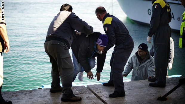 Italian coast guards help an immigrant o