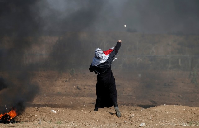 Female demonstrator hurls stones at Israeli troops during a protest where Palestinians demand the right to return to their homeland, at the Israel-Gaza border, east of Gaza City