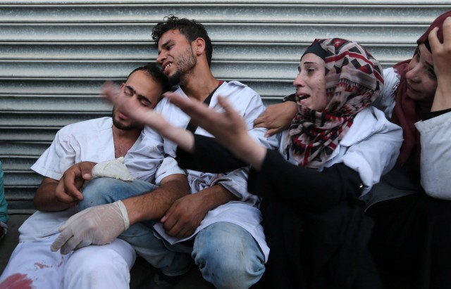 Colleagues of Palestinian medic Abdullah Al-Kotati, who was killed while trying to help wounded protesters at the Israel-Gaza border, react at a hospital in the southern Gaza Strip