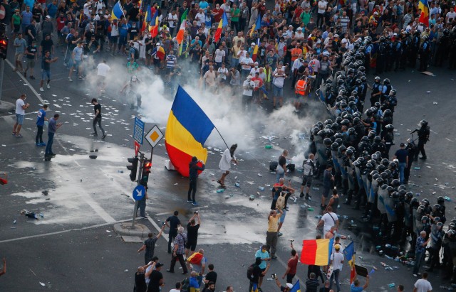 Protesters stand in front of police during a demonstration in Bucharest