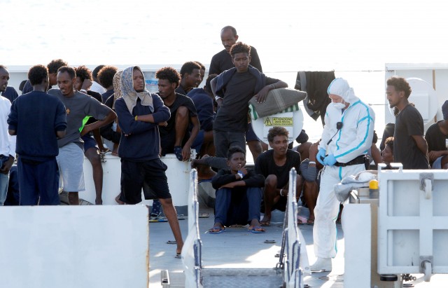 Migrants wait to disembark from the Italian coast guard vessel "Diciotti" at the port of Catania
