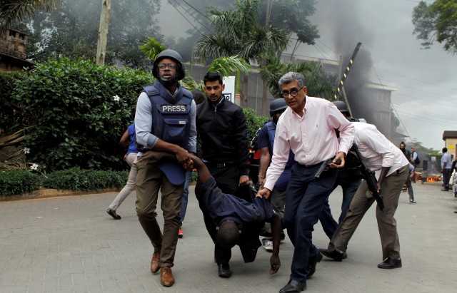 Rescuers and journalists evacuate an injured man from the scene where explosions and gunshots were heard at the Dusit hotel compound, in Nairobi