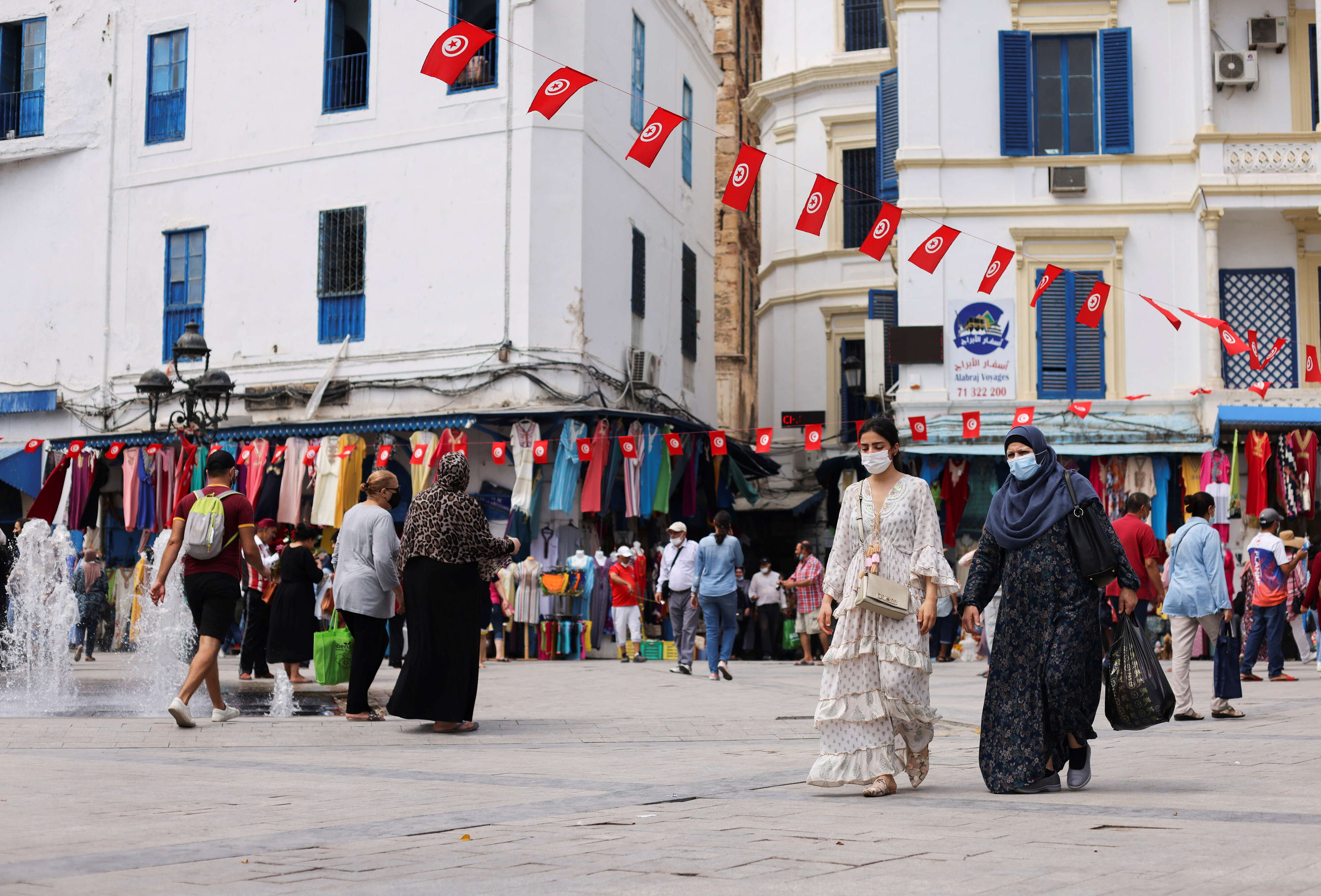 People wearing protective face masks walk past shops, amid the coronavirus disease (COVID-19) outbreak, in the Old City of Tunis